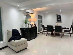 A modern living room with a sofa, dining table, chairs, a black cabinet, a mirror, and a framed artwork on the wall. - Casa grande céntrica 19 huéspedes wifi 500Mbps (Matamoros)