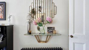 A wall-mounted console table with a vase of flowers, a decorative mirror, and a framed picture. - Exquisite 2 Bedroom Flat in Notting Hill (London)
