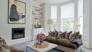 A living room with a fireplace, a sofa set, a coffee table, and a bookshelf. - Exquisite 2 Bedroom Flat in Notting Hill (London)
