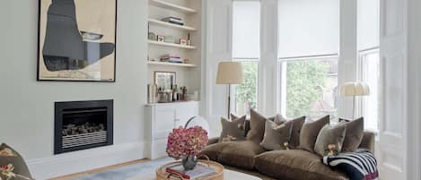 A living room with a fireplace, a sofa set, a coffee table, and a bookshelf.