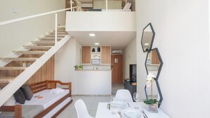 Eine moderne Wohnung mit einer Treppe zu einem Schlafzimmer im oberen Bereich, einem Essbereich mit Tisch für zwei Personen und einer Küche mit Holzschränken.