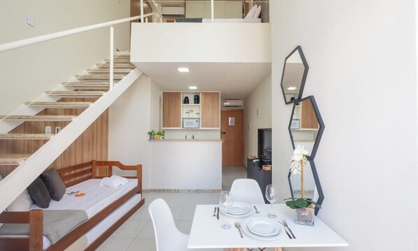 Un intérieur moderne comprenant un coin repas, un escalier et une cuisine.