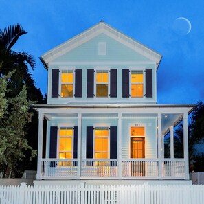 Une maison à deux étages avec un porche, de nombreuses fenêtres et un numéro de maison bien visible.