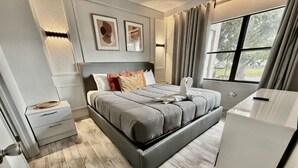 Une chambre moderne avec un lit, des tables de chevet, une commode et une fenêtre avec des rideaux.