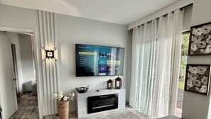 Un salon moderne doté d’un téléviseur à écran plat fixé au mur, d’une cheminée et d’un coin salon confortable.