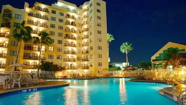 Un hôtel doté d’une piscine, de plusieurs balcons et de palmiers.