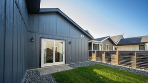 En moderne bygning med grå facade, skydedør indgang og en lille patio med grus og græsplæne.