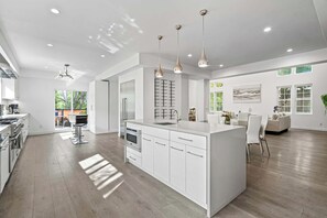 Open-plan kitchen — Center island with sink, pendant lights, and dining area beyond - Sherman Oaks 5BR | Valley Views + Fire Pit | C&C (Los Angeles)