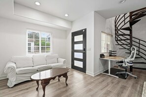 Sitting room — White rolled-arm sofa and wood coffee table with work desk beside spiral stair - Sherman Oaks 5BR | Valley Views + Fire Pit | C&C (Los Angeles)