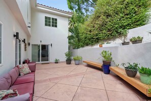 Rear courtyard — Patio seating area with red cushion furniture facing sliding glass door - Sherman Oaks 5BR | Valley Views + Fire Pit | C&C (Los Angeles)