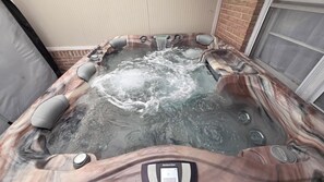 A hot tub with a control panel, surrounded by a brick wall and a window. - Luxury 3-bedroom house with 2 car Garage for use in Car Show Carlisle, PA (Carlisle)