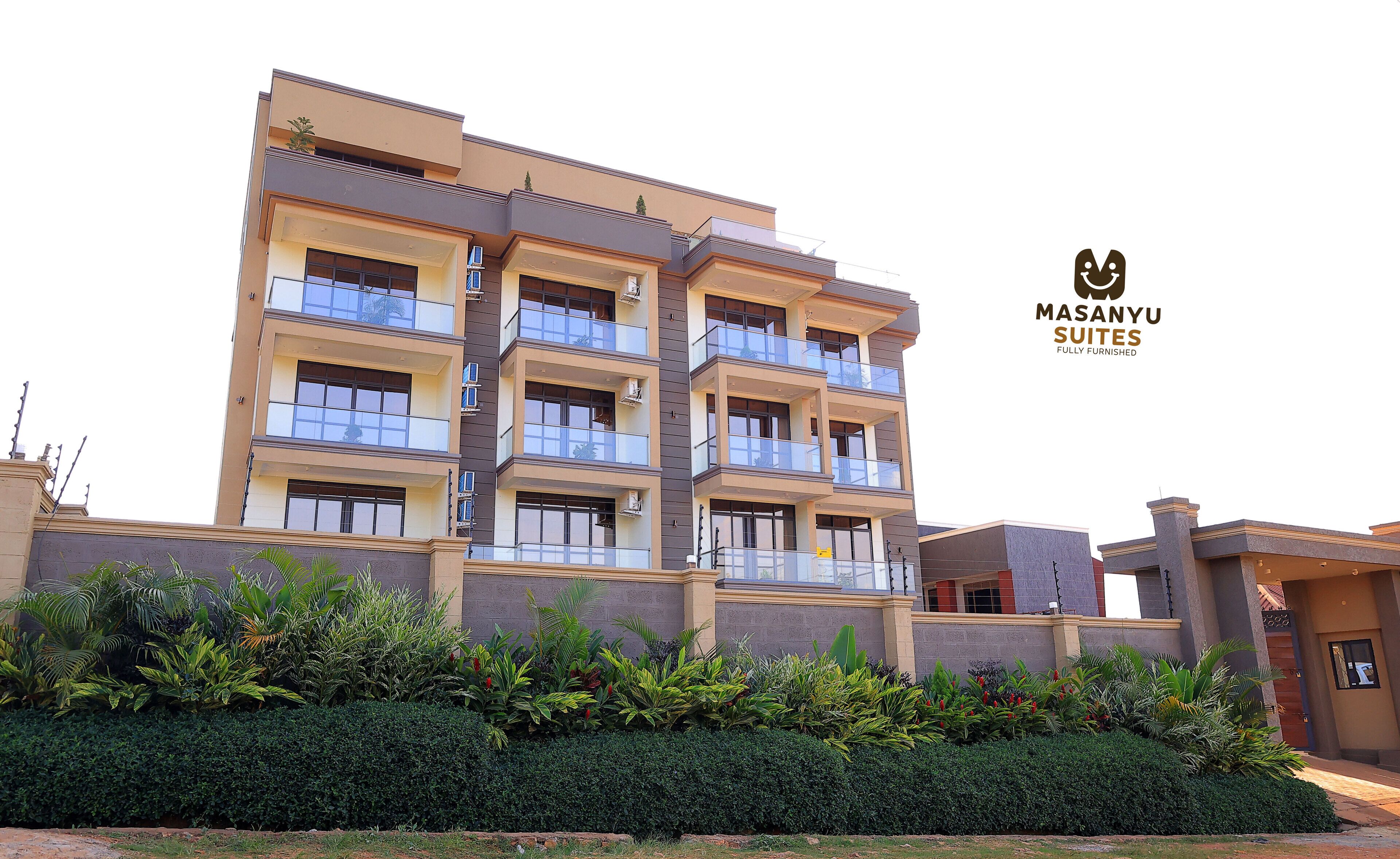 A multi-story building with balconies, air conditioning units, and a logo for Masany Suites.