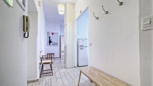 Käytävällä on puinen penkki, jääkaappi ja ovi, joka johtaa toiseen huoneeseen.