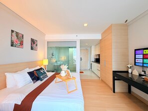 Une chambre d’hôtel moderne équipée d’un lit, d’un bureau, d’une télévision et d’un espace douche.