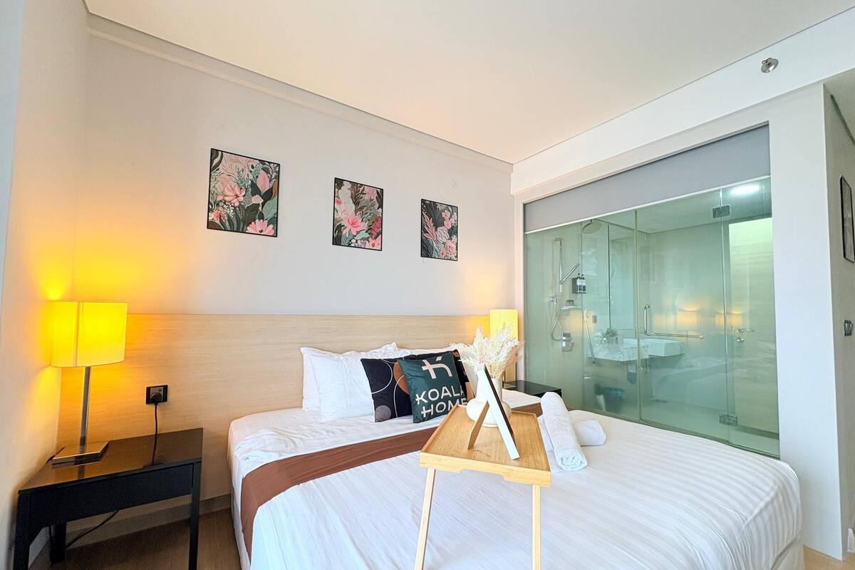 Een hotelkamer met een bed, nachtkastje, lamp en een douchecabine.