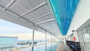 A rooftop infinity pool with a view of the city skyline, a covered walkway, and a lifebuoy on the wall. - The Straits Residence by Koala (Malacca City)