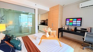 A modern hotel room with a large bed, a desk, a TV, and a view of the city through the glass door. - The Straits Residence by Koala (Malacca City)