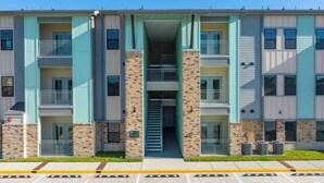 Un immeuble d’appartements à plusieurs étages, doté d’un escalier central, de balcons et d’un parking situé à l’avant.