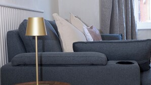 A modern living room with a grey sofa, a round wooden side table, and a gold floor lamp. - Estokova Haven sleeps up to 9 - Free parking (Swindon)