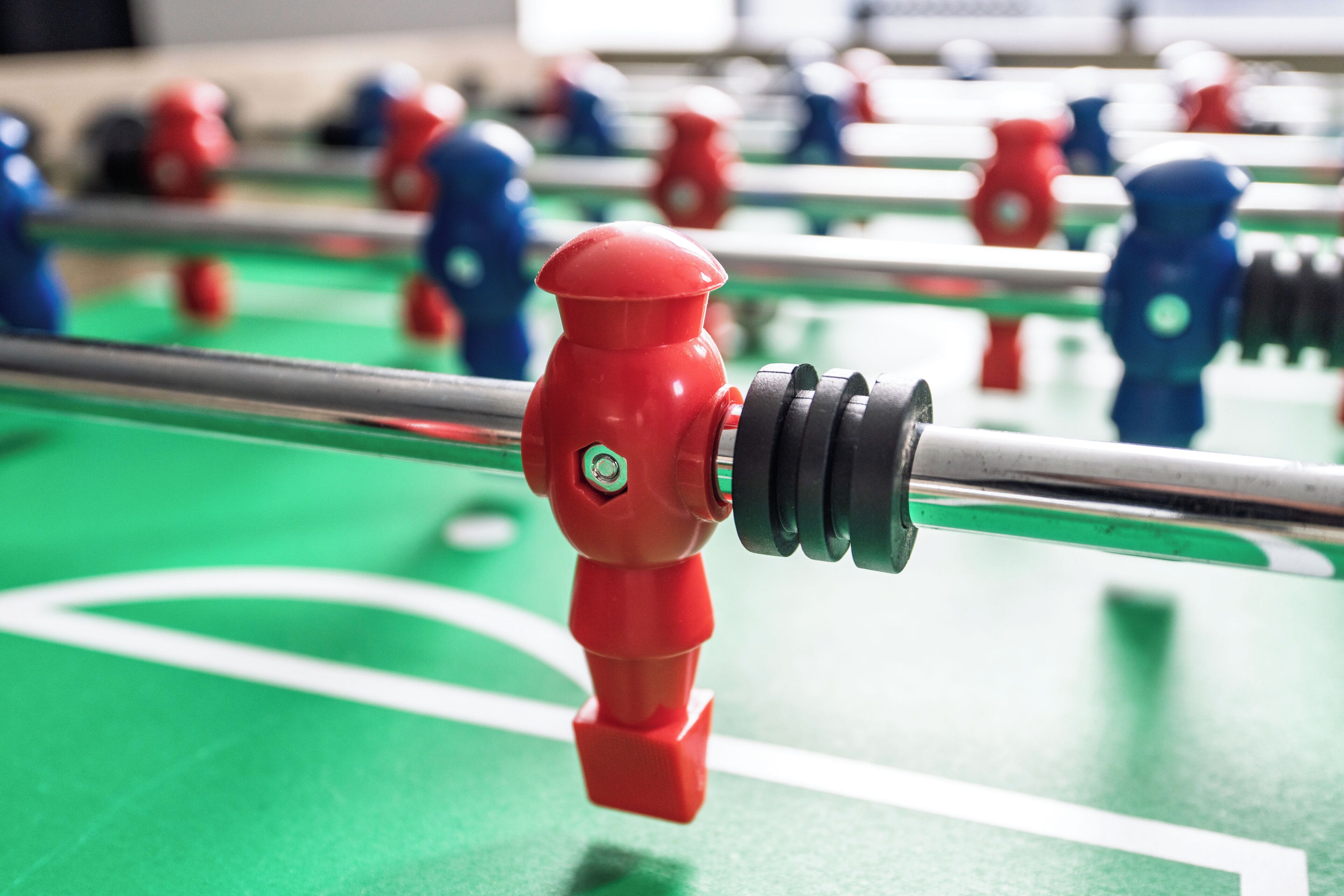 A close-up of a foosball table with red and blue player figures.