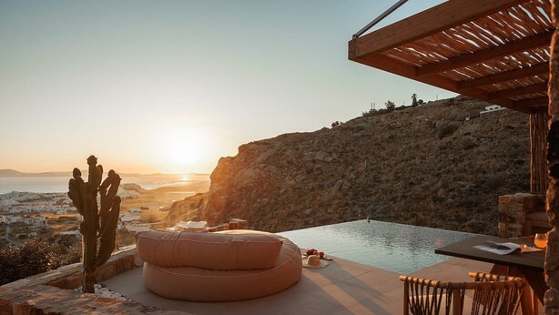 Zona de piscina amb vista al capvespre, un cactus i una pèrgola de fusta.