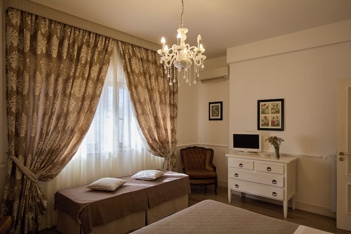A bedroom with a bed, a chair, a dresser, and a television.