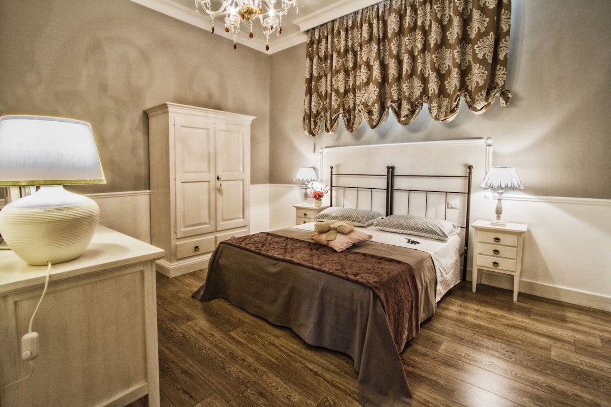 A bedroom with a bed, bedside tables, a wardrobe, and a chandelier.