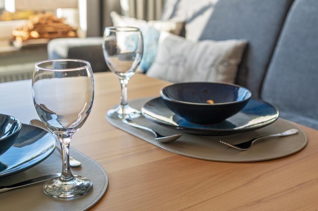 Uma mesa de jantar com uma tigela, uma taça de vinho e talheres.