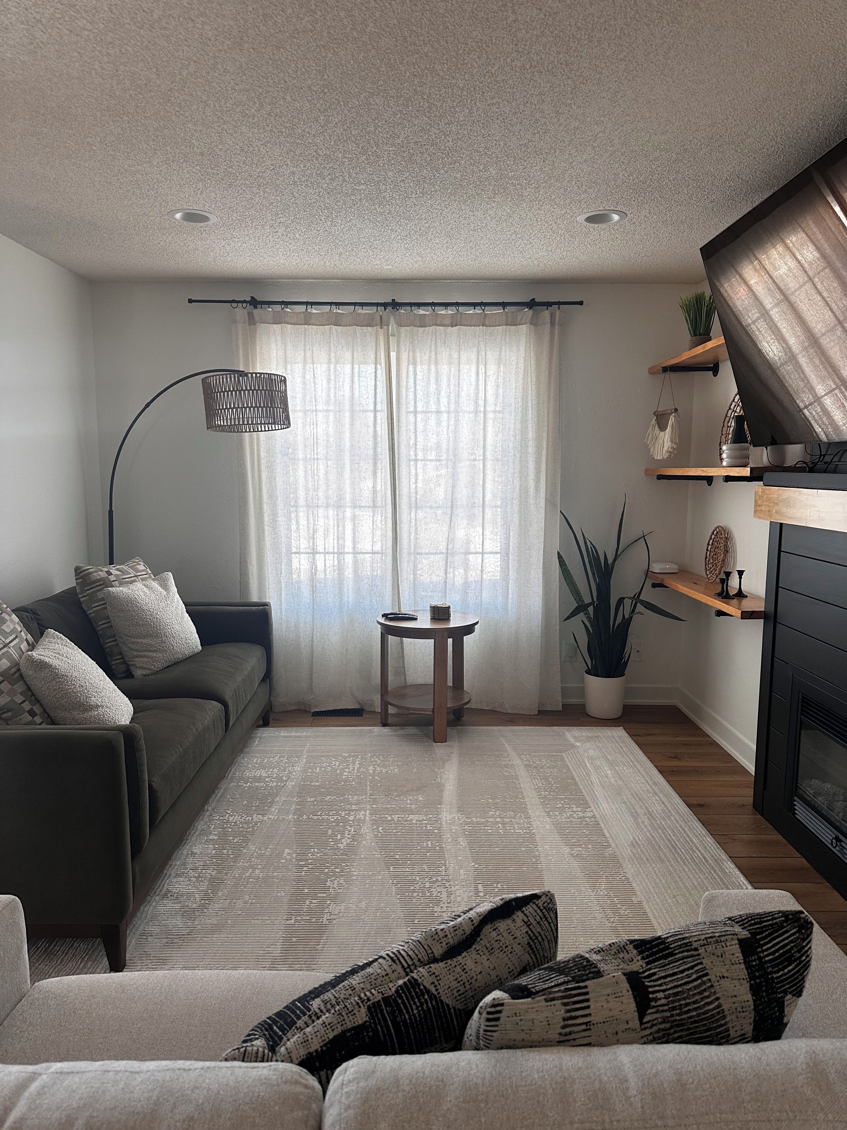 Ein modernes Wohnzimmer mit einer Couch, einem Couchtisch, einer Stehlampe und einem Kamin.