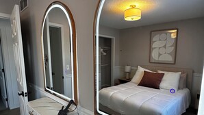 Une chambre à coucher avec un lit, une table de chevet avec une lampe, un miroir et une armoire.
