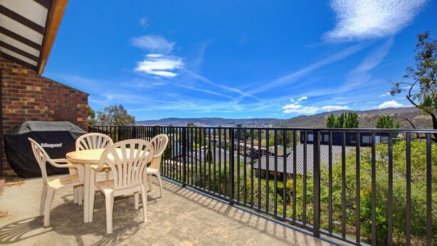 Ein Balkon mit Grill, Sitzgelegenheit und einem schönen Ausblick auf ein Tal.
