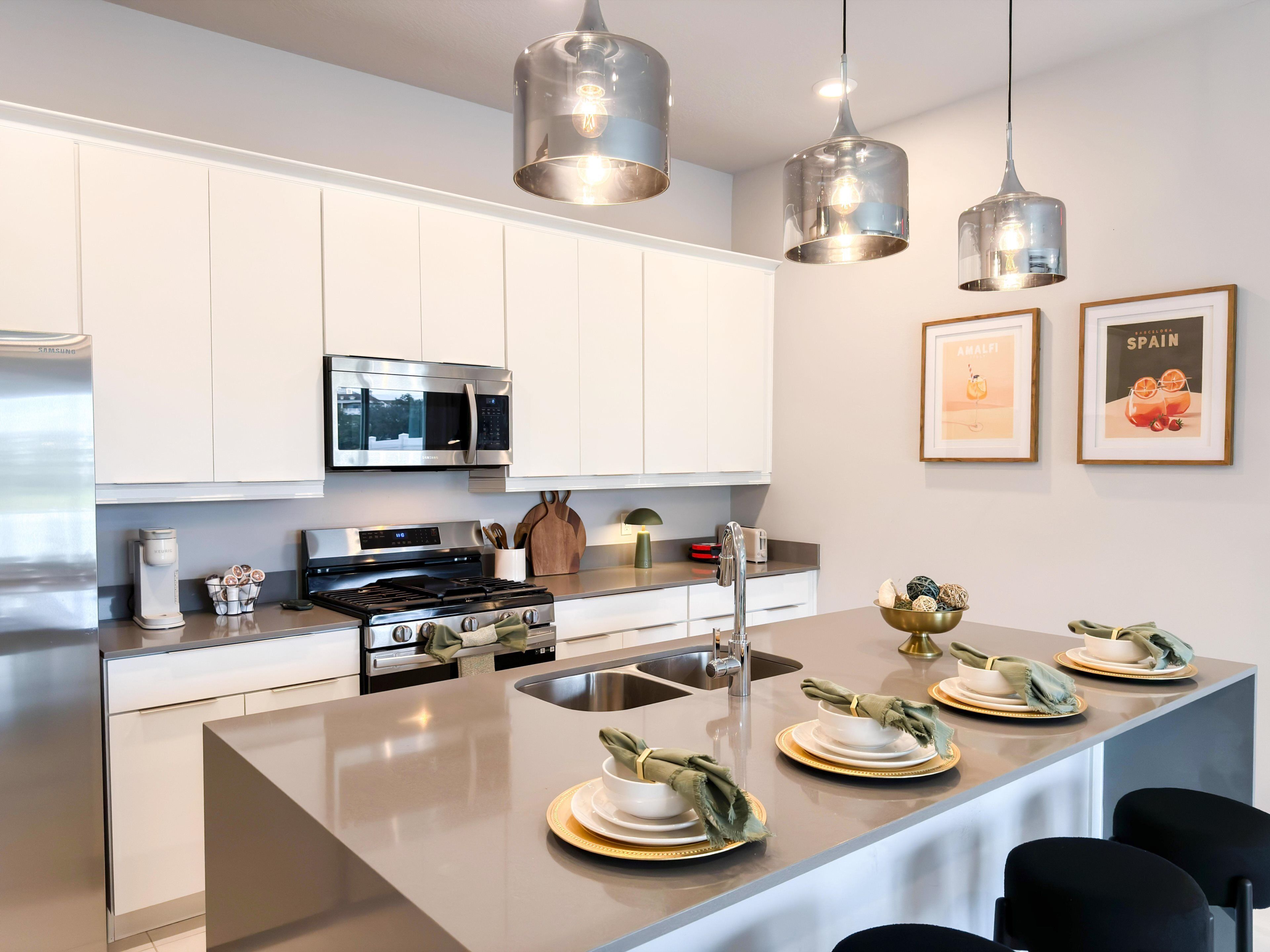 A modern kitchen with white cabinets, stainless steel appliances, and a central island with dining setup.