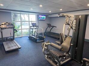 Un gimnasio con cintas de correr, bicicletas estáticas y máquinas de pesas.
