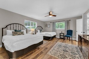 A bedroom with two beds, a ceiling fan, a chair, a dresser, and a window with blinds. - Boating, Hiking, Bike, and Golf at Rogers Getaway (Rogers)