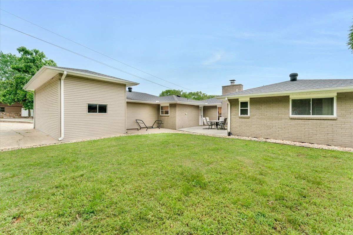 A two-story house with a covered patio area and a lawn.