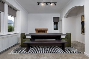 A modern room with a dark wooden table, green upholstered chairs, a fireplace, and a patterned rug. - Stirling Edwardian House: Fireplace/Garden/Parking (Stirling)