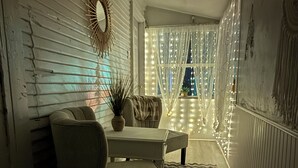 Un couloir chaleureux et faiblement éclairé, avec un fauteuil moelleux, une petite table et un miroir décoratif au mur.