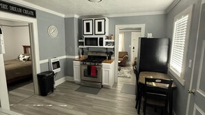Une cuisine compacte avec des meubles blancs, un four à micro-ondes et une cuisinière. Il y a également un coin repas avec une table et des chaises.