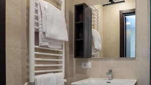 Ein modernes Badezimmer mit einem weißen Handtuchhalter, einem Spiegel und einem Waschbecken.