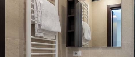 Un baño moderno con toallero blanco, espejo y lavabo.