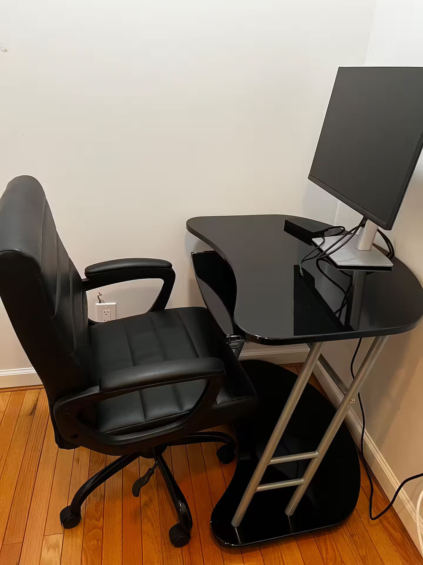A black office chair and a black desk with a monitor.