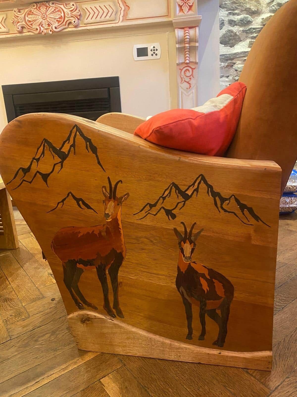 Een houten stoel met houtsnijwerk van bergen en dieren.