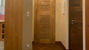 Ein Flur mit Holztüren, einem Chandelier und einem roten Bett im Vordergrund.