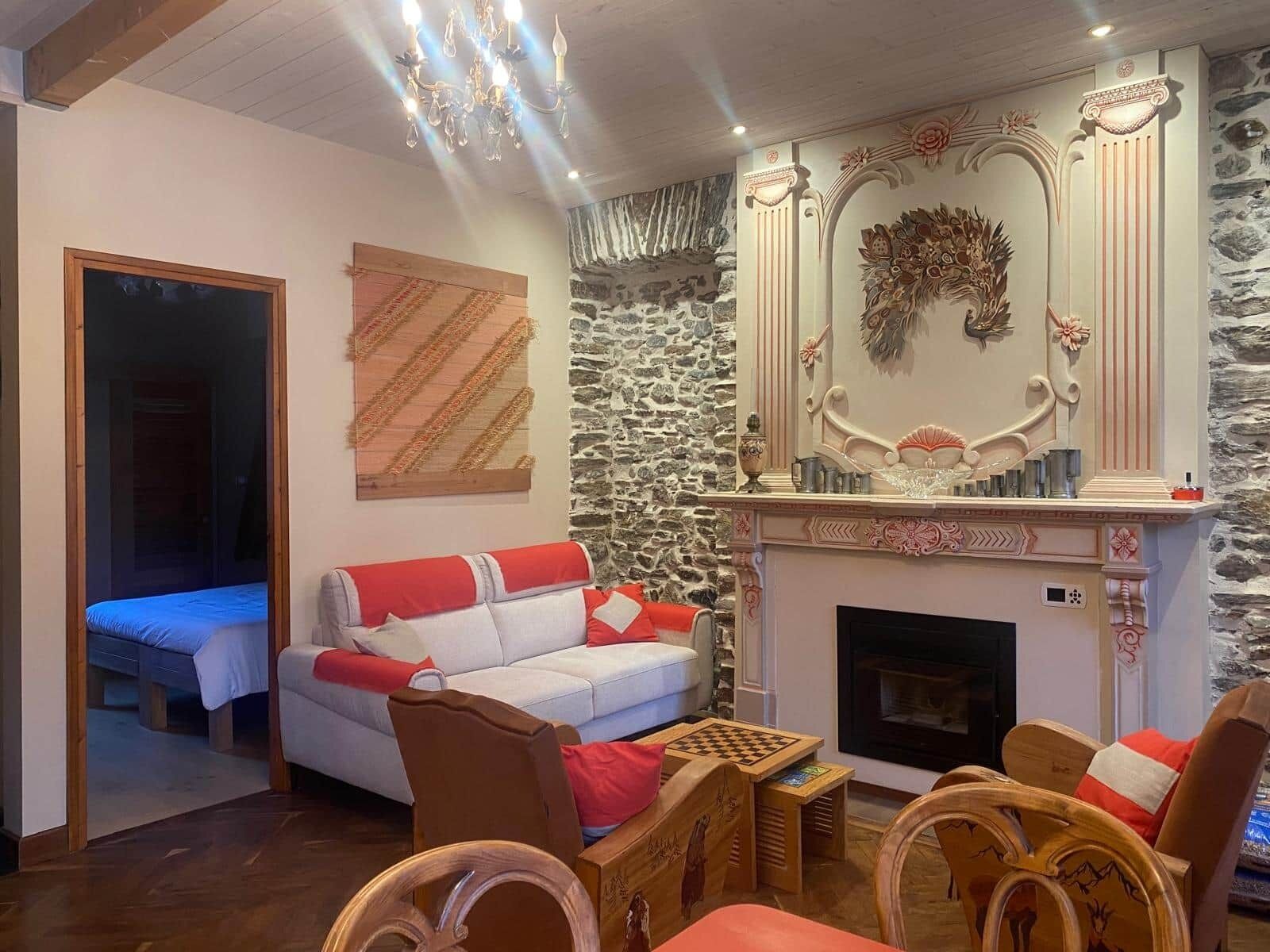 A room with a fireplace, a sofa, a wooden table, and a mirror with decorative elements.