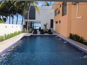 A swimming pool with lounge chairs, a white building, and palm trees. - Sofy House - San Diego Beach (San Diego)