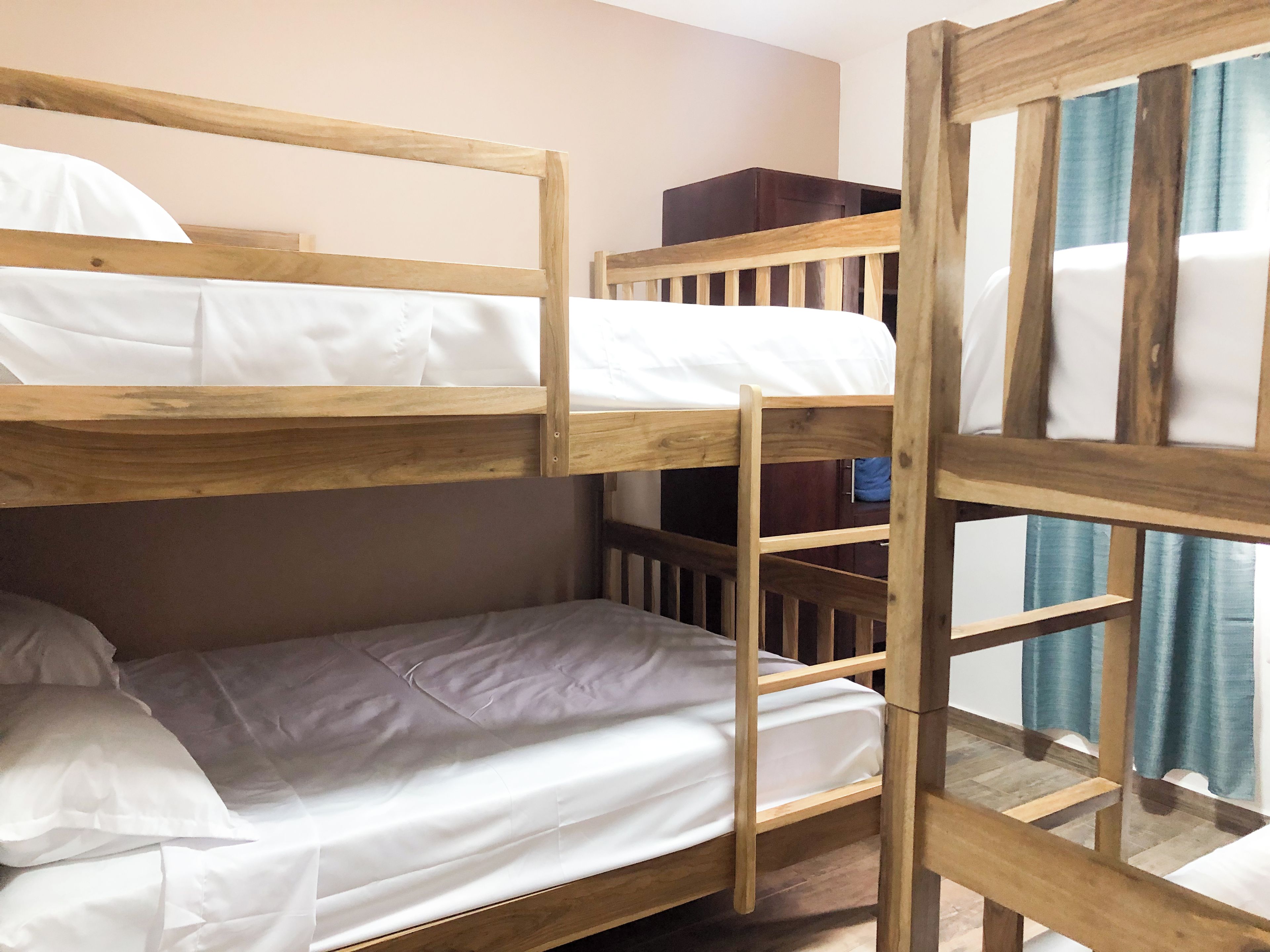 Una cama individual con ropa de cama blanca, cabecera de madera y una pequeña escalera de madera.