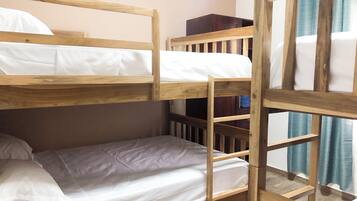 Una cama individual con ropa de cama blanca, cabecera de madera y una pequeña escalera de madera.