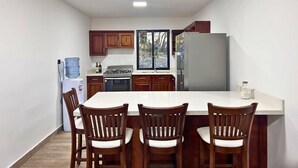 Una cocina con una isla central, armarios de madera, un refrigerador y un dispensador de agua.