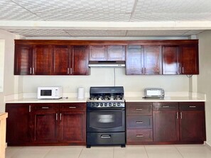 Una cocina con armarios de madera oscura, una estufa negra, un microondas blanco y un tostador.