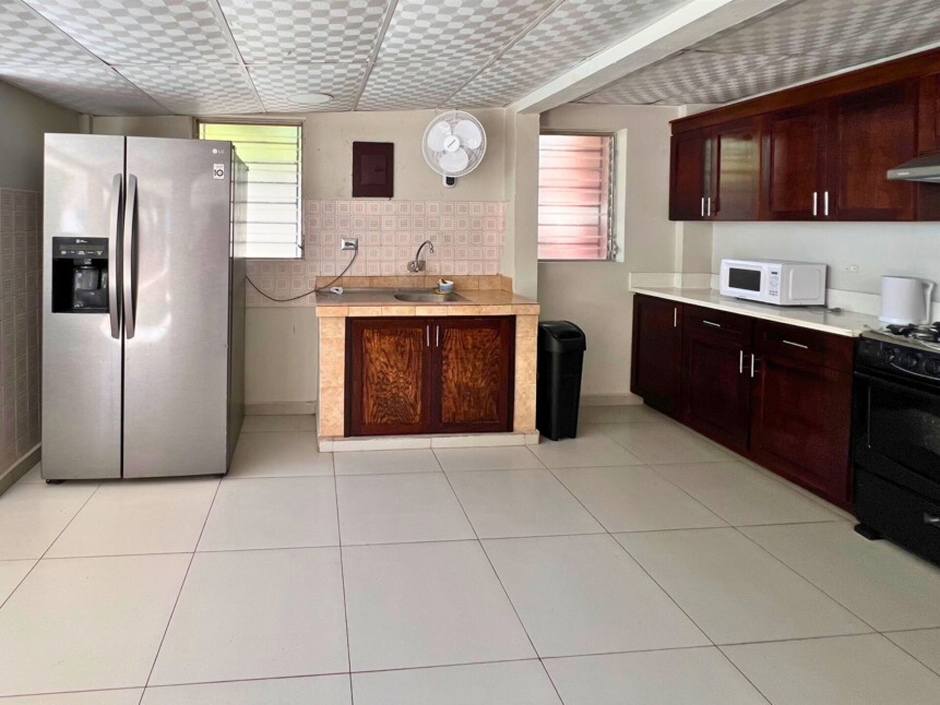 Una cocina con refrigerador, microondas, pileta y alacenas.